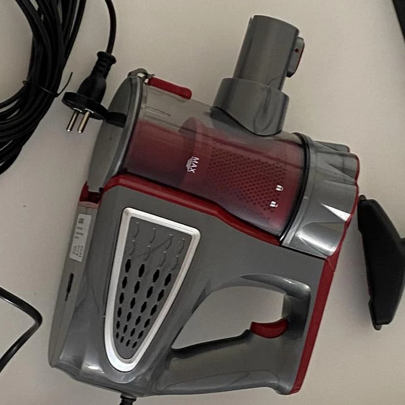 The body of the vacuum in close-up: dust container, side grille, handle with trigger