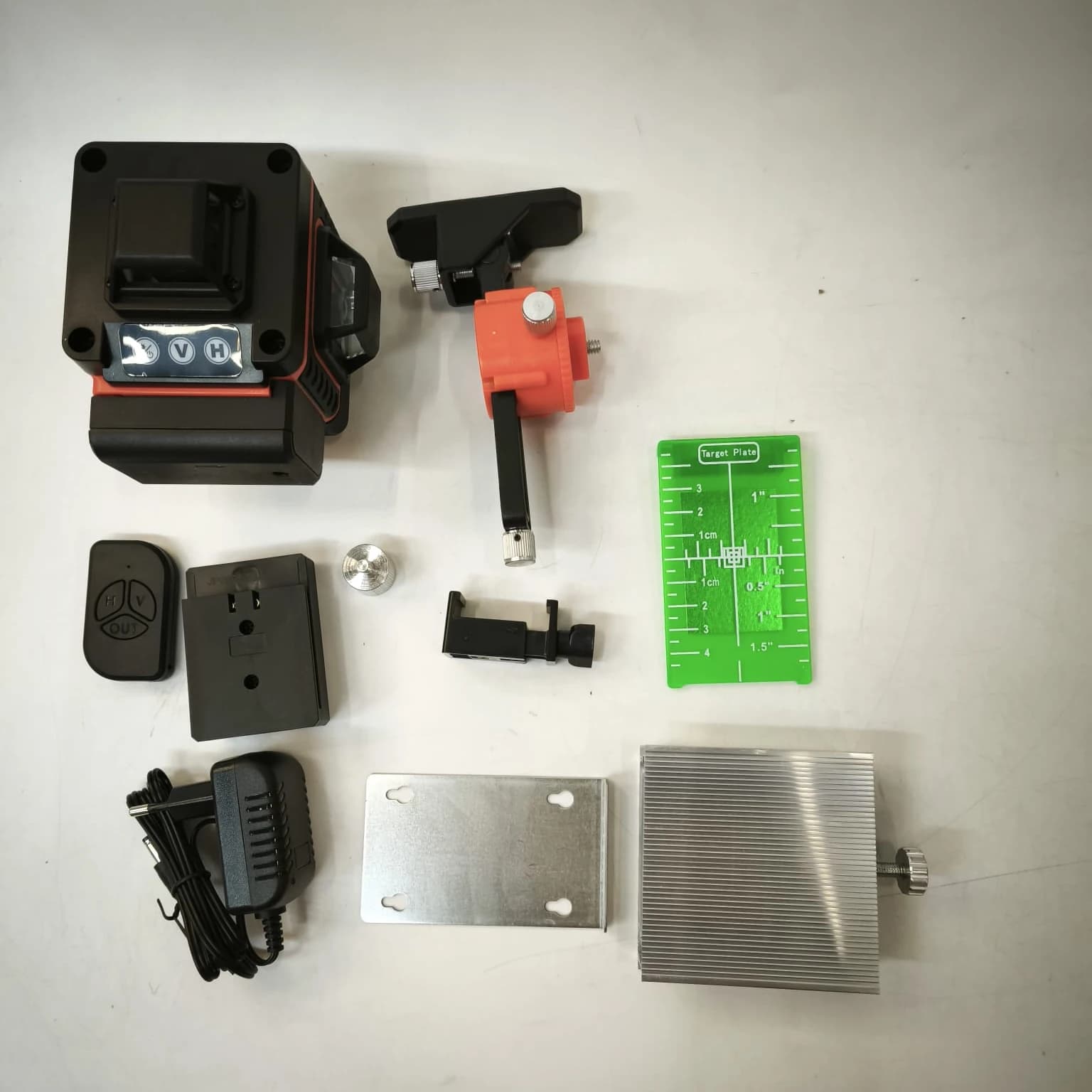 Everything in the box laid out on a table: level, battery, remote control, charger, bracket, platform and target plate