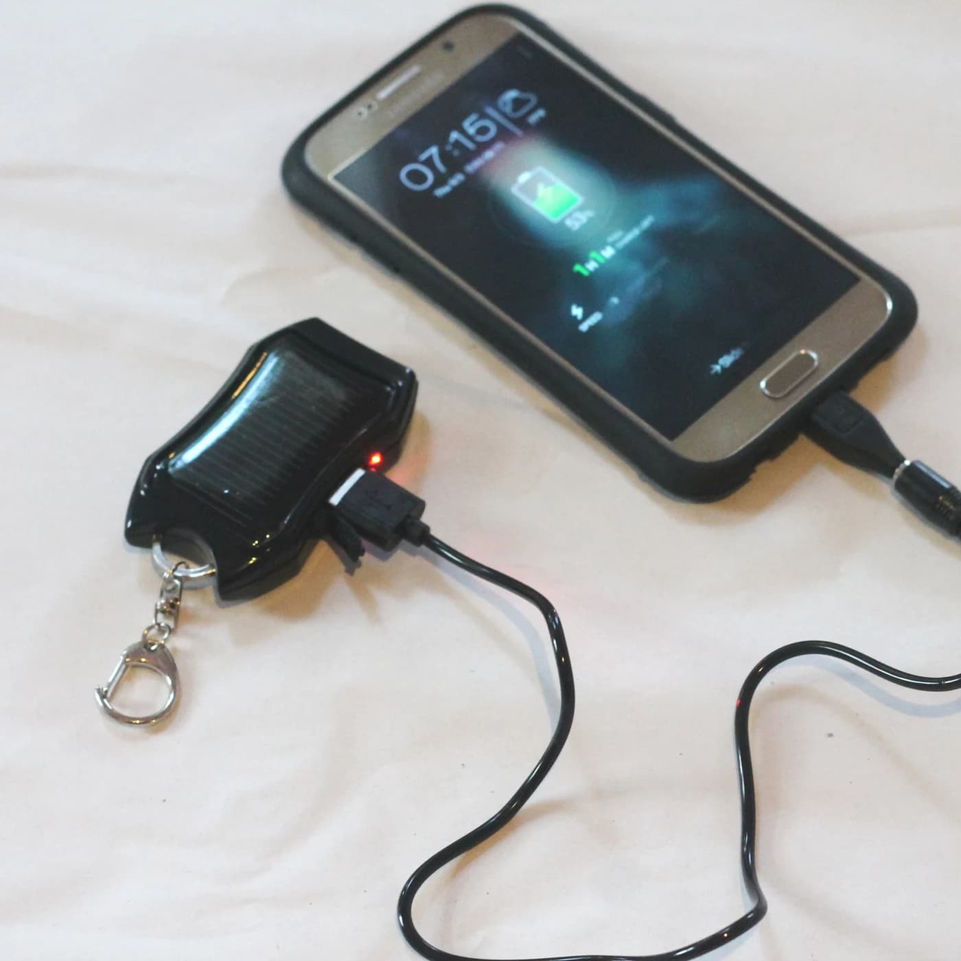 The keyring power bank charging a smartphone through a cable